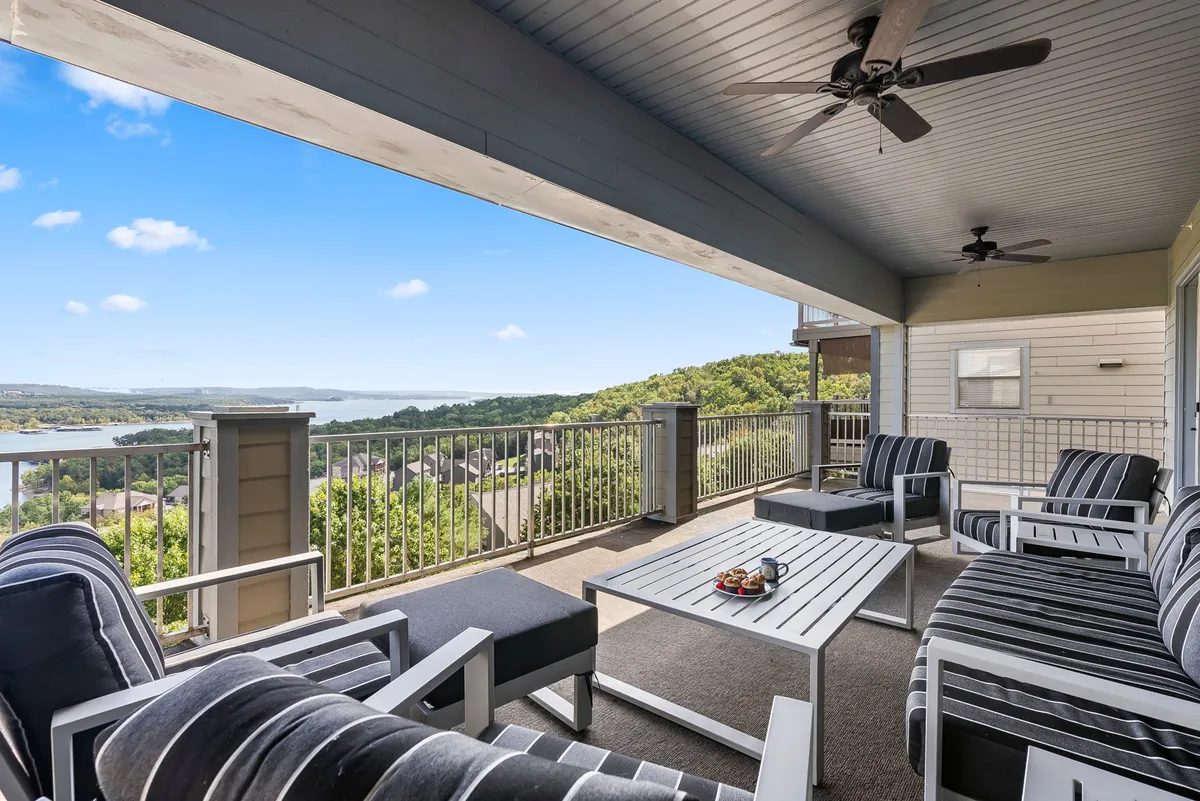 A comfortable and inviting seating area is arranged on a deck or balcony, centered around a coffee table set with refreshments. The scene provides a sweeping, panoramic view of Table Rock Lake, inviting guests to relax, socialize, or enjoy a drink while soaking in the serene landscape. The mood is tranquil and refreshing, ideal for unwinding at any time of day.