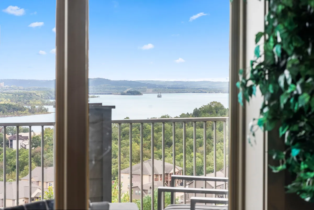 A peaceful balcony view featuring the sparkling lake, gentle hills, a sturdy railing, and verdant foliage. The scene is tranquil and inviting, perfect for enjoying drinks, watching boats go by, or observing sunsets as a group.
