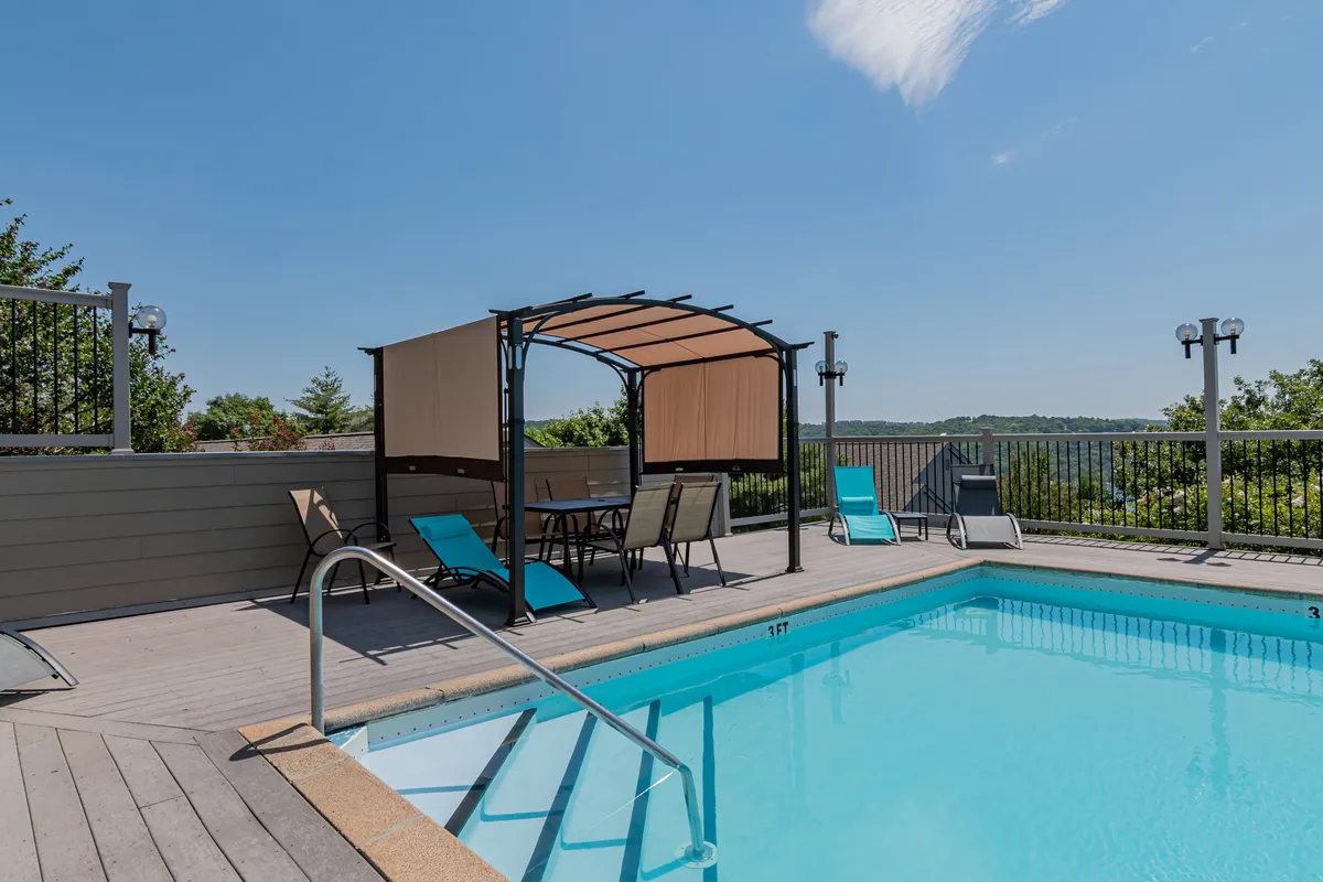 A vibrant exterior scene featuring the resort's large outdoor swimming pool, surrounded by lounge chairs, a cabana, and landscaped views. The area is bathed in sunlight, suggesting a lively, family-friendly atmosphere perfect for summer fun.