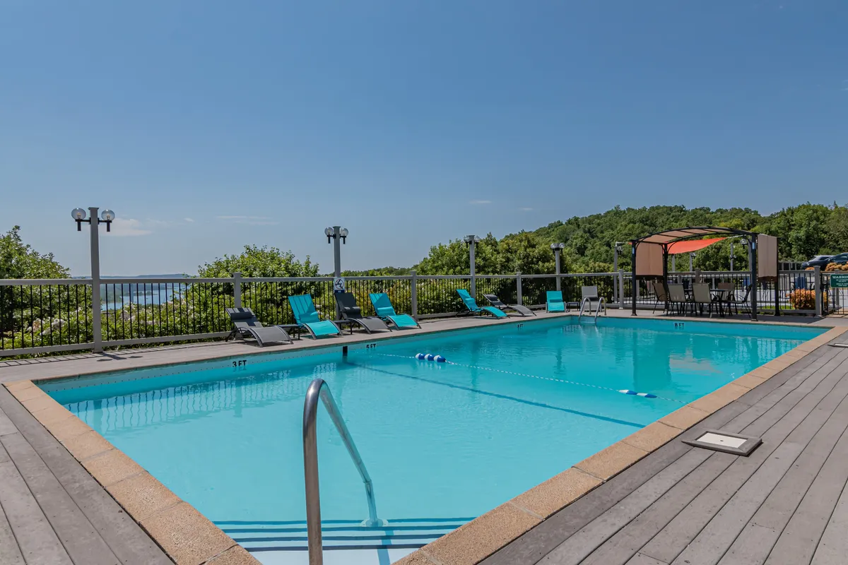 This exterior shot showcases the resort’s swimming pool area with lounge chairs and a canopy seating space. The pool is just steps away from the private deck, reinforcing the connection between the personal outdoor space and shared resort amenities. The setting suggests opportunities for swimming, sunbathing, or enjoying a poolside meal in a relaxed environment.