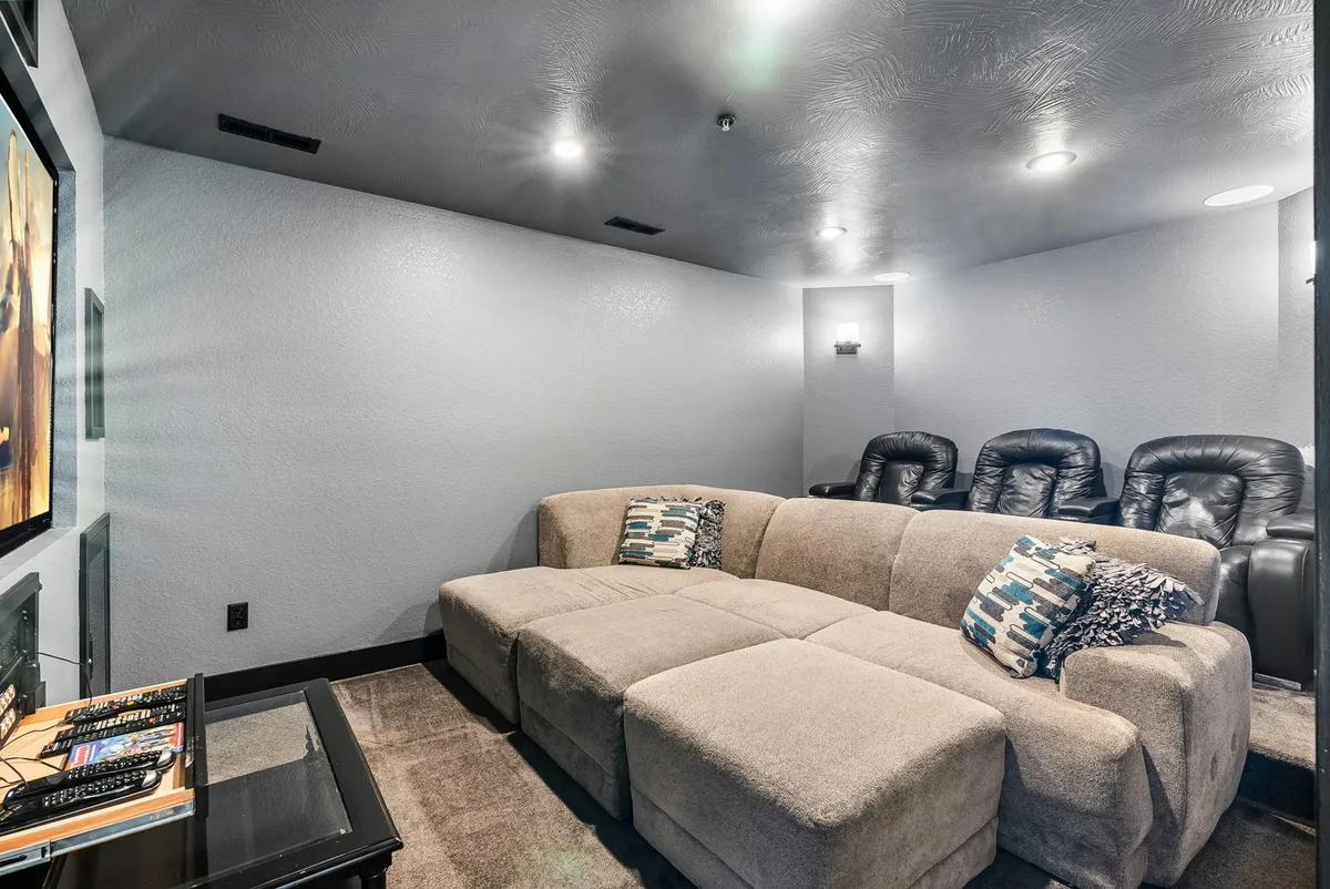 A dedicated home theater room with theater-style seating, a large sectional couch, and a prominent screen with remote controls, creating an environment perfectly suited for immersive movie nights and group entertainment.