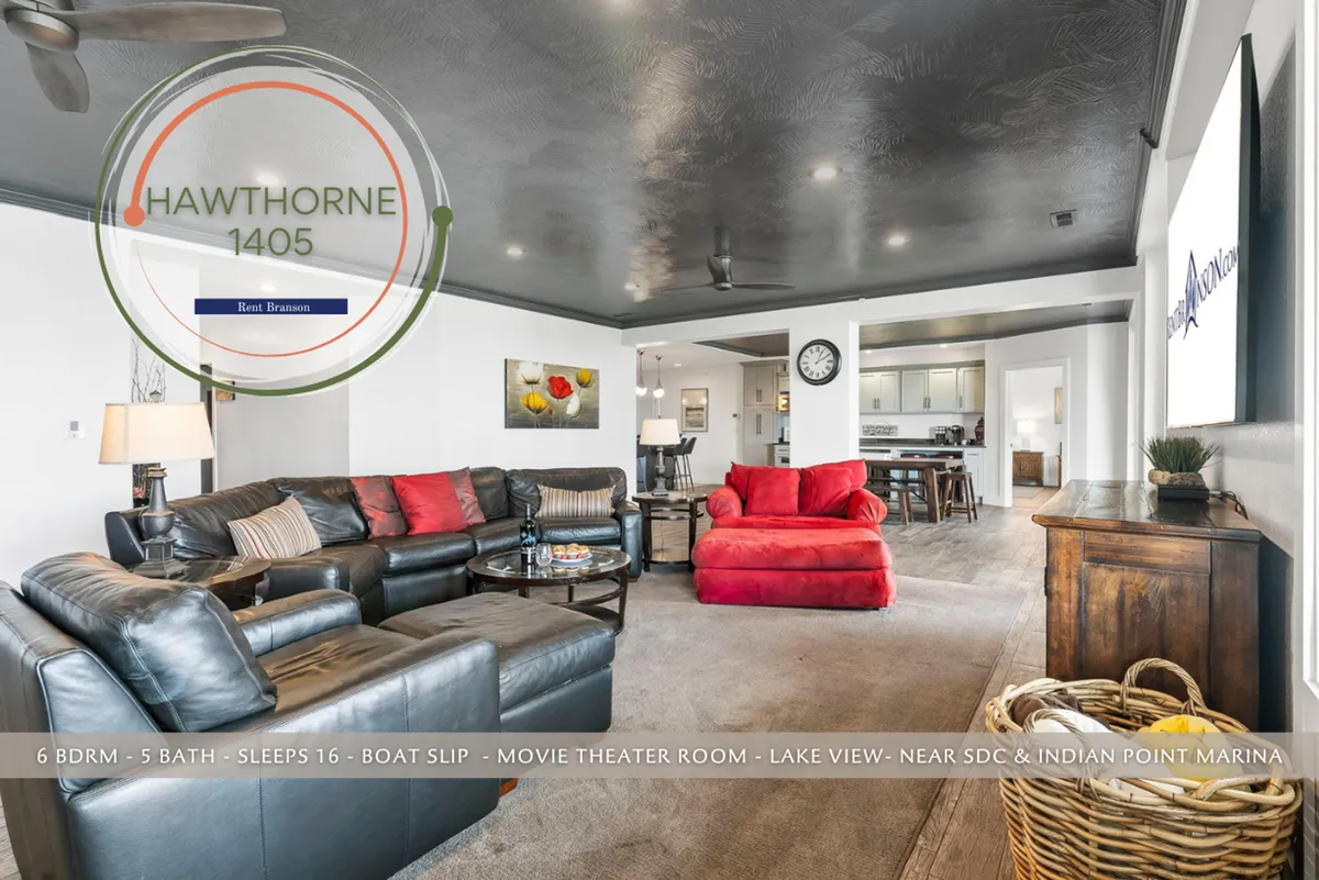 An inviting living space with a large sectional sofa, a red accent chair, a coffee table, and eye-catching artwork on the wall. The kitchen area is visible in the background, emphasizing the open-concept design perfect for family gatherings, game nights, and relaxed evenings.