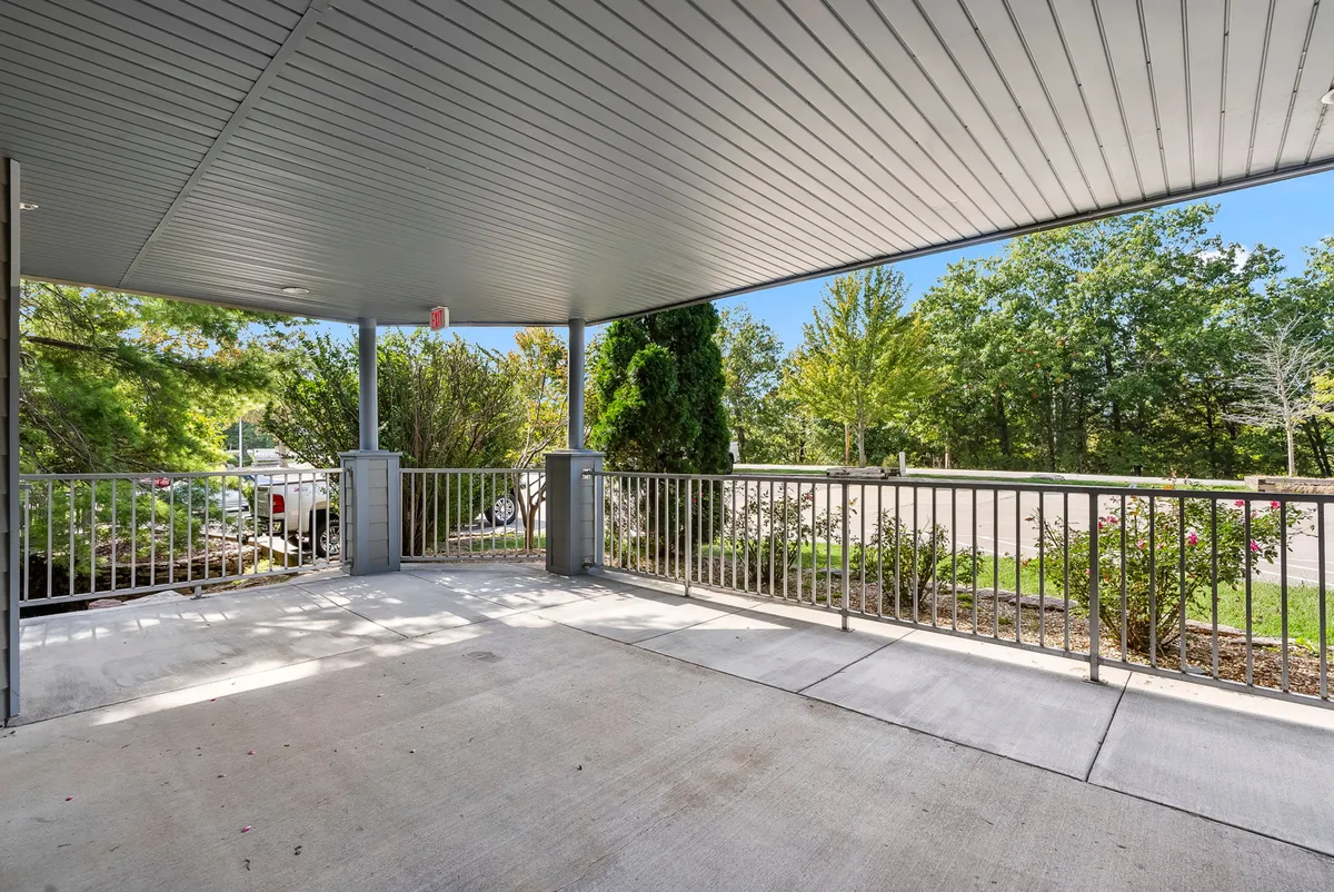 A peaceful covered porch surrounded by greenery, ideal for relaxing with friends or enjoying morning coffee. The inviting setting connects the comfort of the property with the surrounding natural environment.